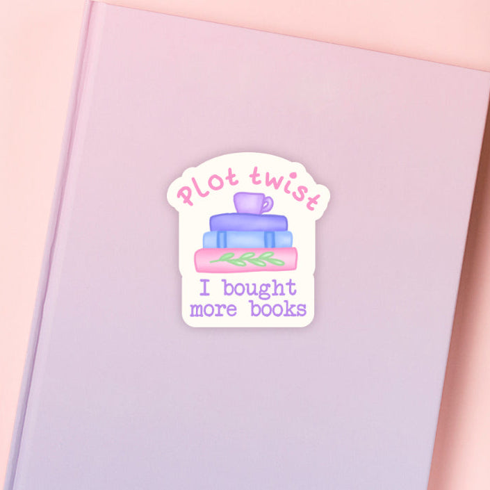 Pastel coloured Sticker with 'Plot twist: I bought more books' text along with a stack of books and a teacup on a pink background